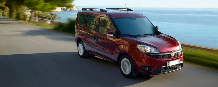 Червоний Fiat Doblo рухається дорогою біля моря